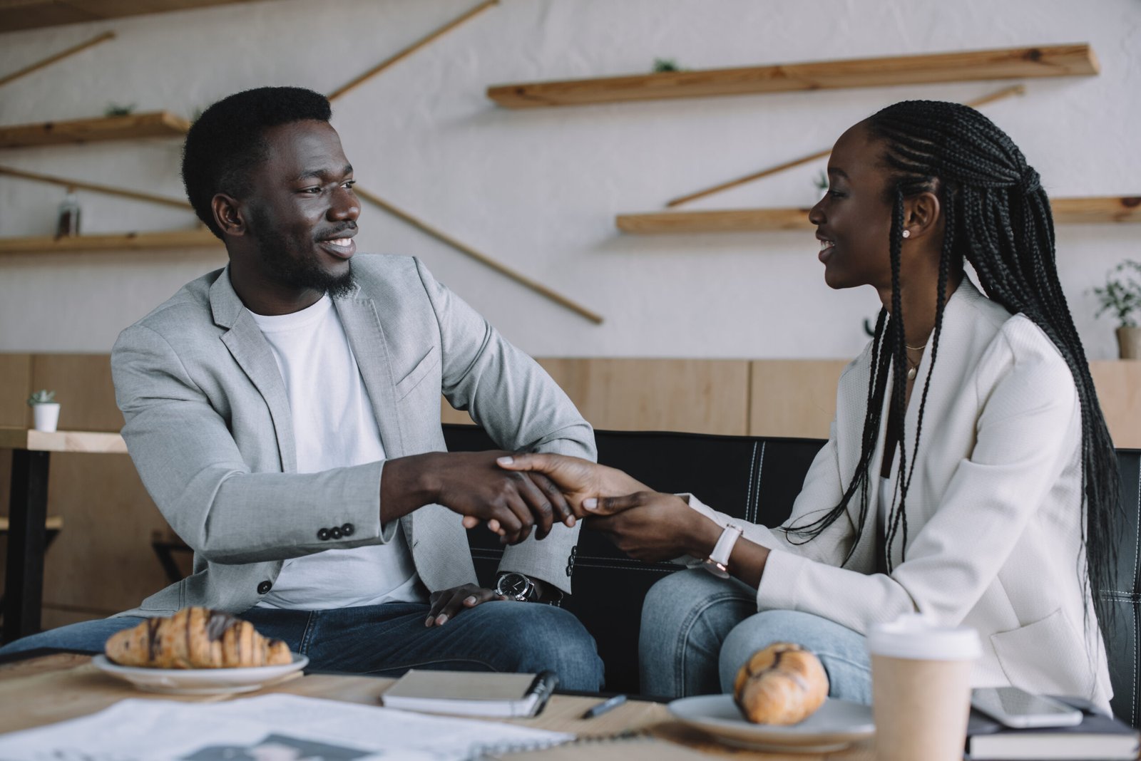 african american business partners shaking hands during business meeting in cafe