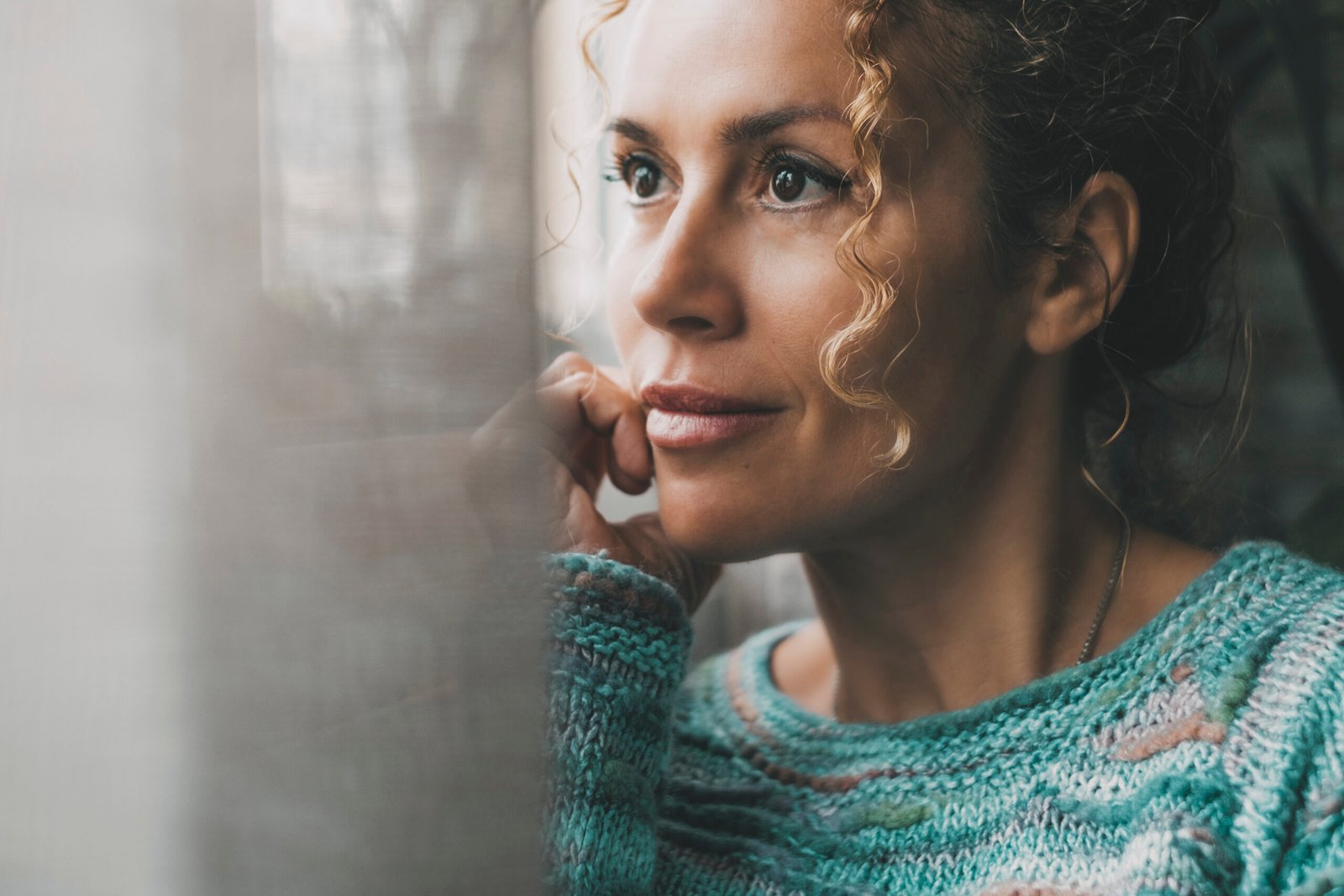 One confident lady contemplate outside the window at home with dreaming and thoughtful expression on face. Portrait of adult female people in indoor thinking leisure activity alone with window light