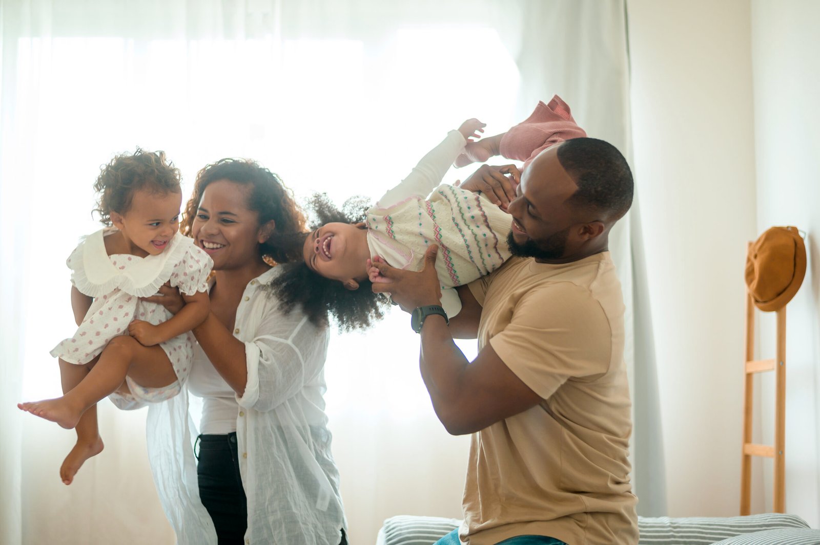 Parents with  little daughters playing on the bed in bedroom