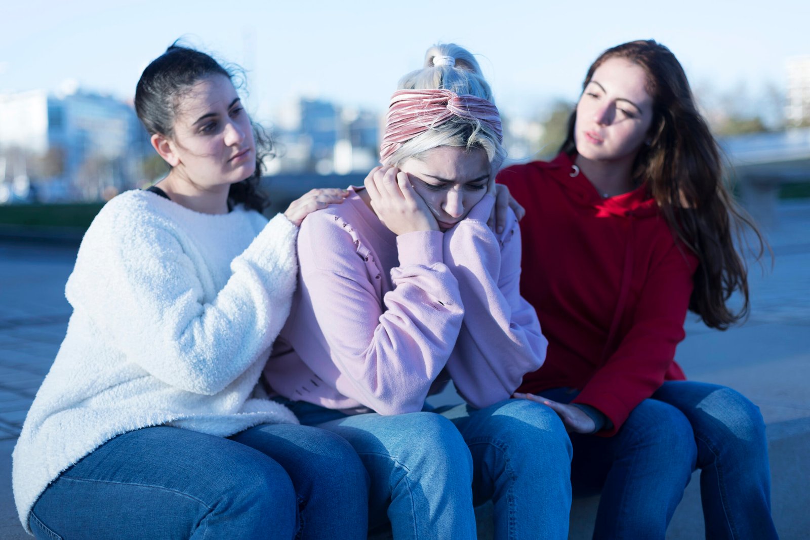 Two friends cheering up young depressed girl