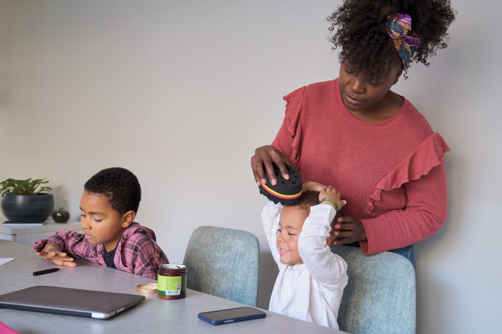 African mother styling her son hair using an afro curl wave or twists sponge.