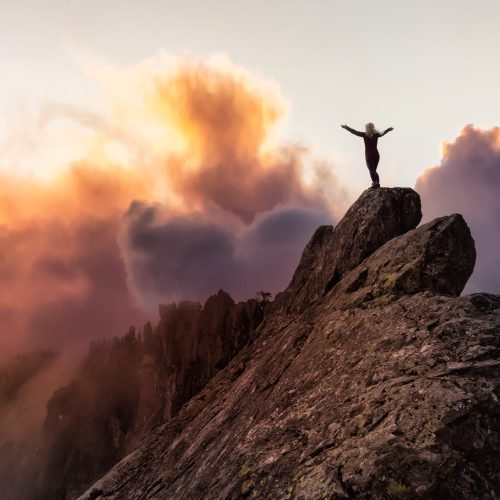 Adventurous Girl on top of a rugged rocky mountain. Dramatic Colorful Sunrise Sky Art Render. Taken on Crown Mountain, North Vancouver, BC, Canada.