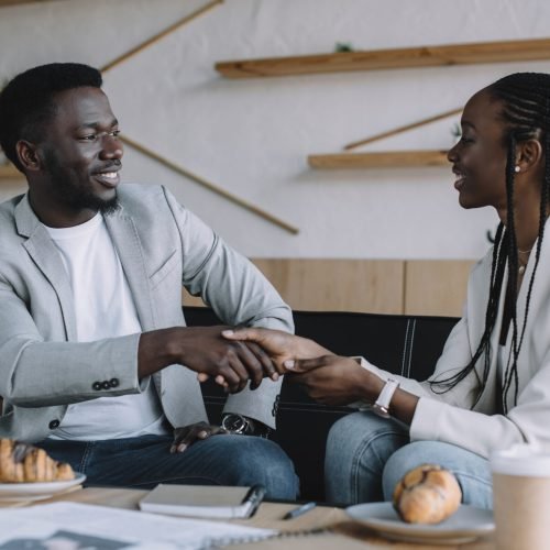 african american business partners shaking hands during business meeting in cafe