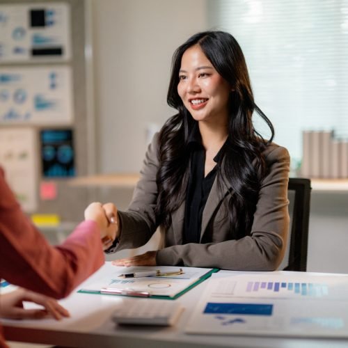 Professional women concluding successful negotiation, exchanging handshake in corporate workspace