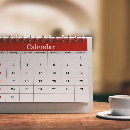 Desk calendar, a smartphone and a cup of coffee on a wooden table. 3d illustration