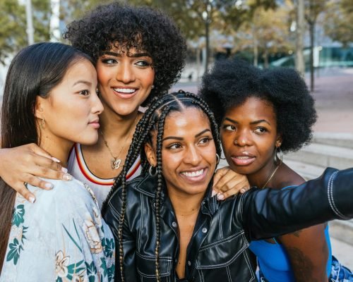 Cute multi-ethnic women and transgender person taking a selfie together in the city