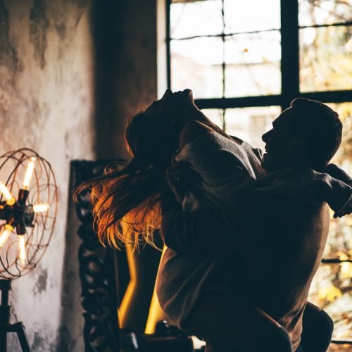 Young man holding woman in his hands. Couple in love at the home.