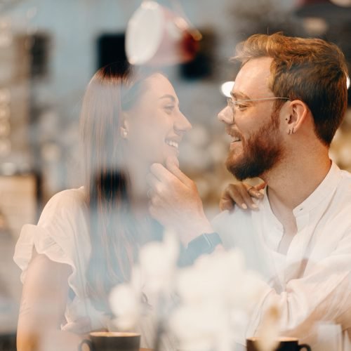 Loving couple in a coffee shop. Happy young couple is drinking coffee and smiling while sitting in a coffee shop