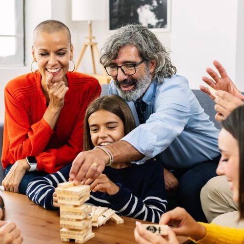 Multigenerational caucasian family having fun playing together at home, sitting together on sofa in living room.