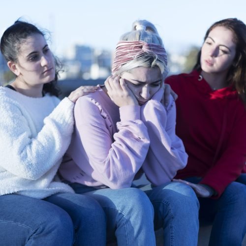 Two friends cheering up young depressed girl
